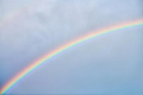 Vibrant rainbow arching across soft cloudy sky Stock Photos