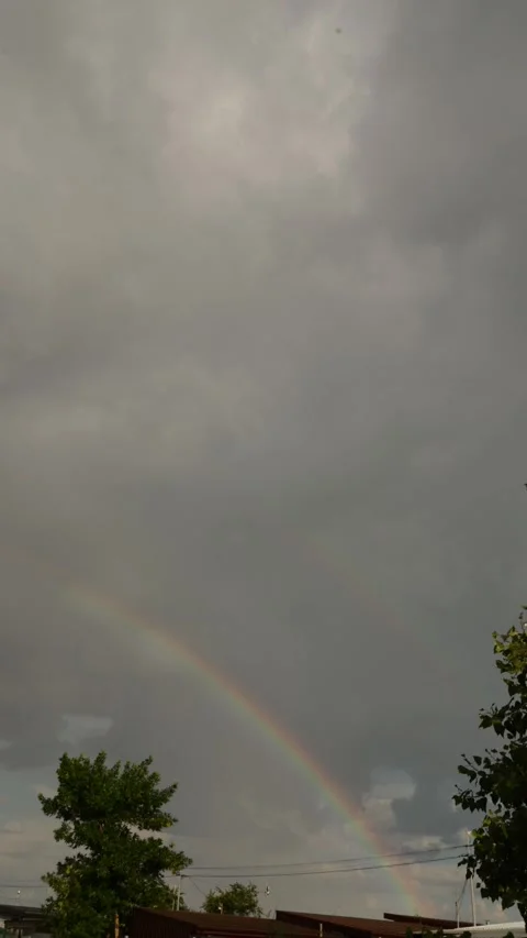 Vibrant rainbow arcs across a cloudy sky after a storm Stock Footage 337129115
