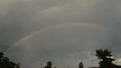 Vibrant rainbow arcs across a cloudy sky after a storm Stock Footage 337129524