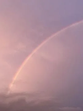 A vibrant rainbow gracefully arches through soft pastel skies, offering a pea Stock Photos