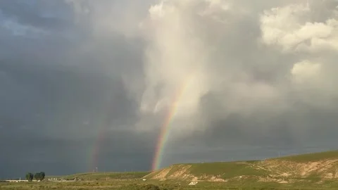 Vibrant Rainbow Over Green Rolling Hills and Dramatic Clouds Xinjiang China Stock Footage 339171582