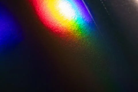 Vibrant Rainbow Reflections on Textured Dark Surface with Colorful Light Pa.. Stock Photos