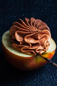 A vibrant red apple features a beautifully crafted chocolate frosting on top, Stock Photos