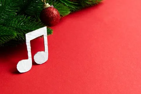 Vibrant red backdrop features lush green pine branches and a playful music no Stock Photos