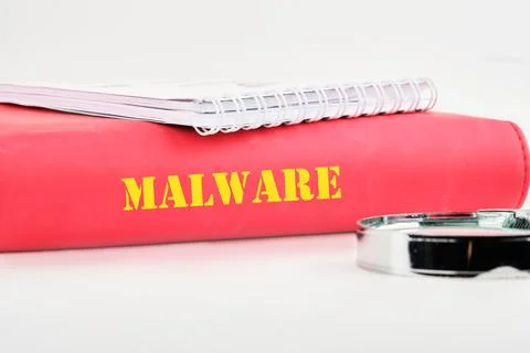 A vibrant red binder labeled 'Malware' sits next to a silver magnifying glass Stock Photos