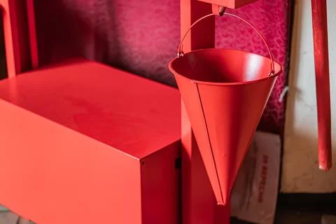 A vibrant red cone-shaped container fire safety shield sits open on a matchin Stock Photos