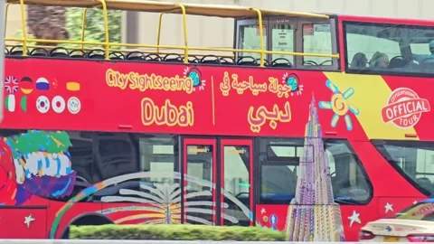 A vibrant red double decker tour bus, adorned with colorful graphics and Arabic Stock Footage 311885522