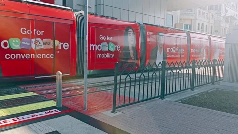 A vibrant red Dubai Tram, adorned with Etisalat branding and Arabic Stock Footage 311765417