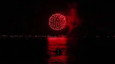Vibrant red fireworks explode over a boat in the bay 스톡 동영상 40648036