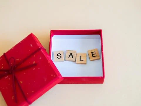 Vibrant red gift box filled with sale letters perfect for holiday promotion.. Stock Photos