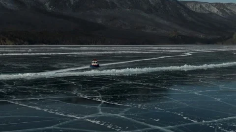 Vibrant Red hovercraft Swiftly Moves Across Icy Black Lake Capturing Dynamic Stock Footage 339184169