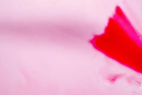 Vibrant red ink bleeding into a soft pink paper texture, creating a minimal.. Stock Photos