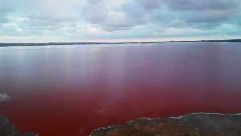 Vibrant red lake under cloudy sky in unique location Stock Footage 320265040