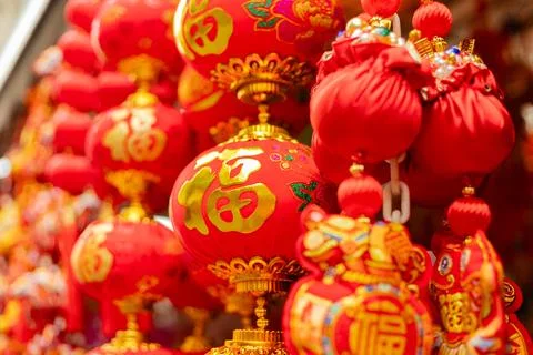 Vibrant red lanterns and decorations hang from stalls in a busy market. Peo.. Stock Photos