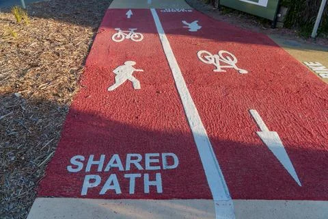 Vibrant red shared path with clear white markings for pedestrians and cycli.. Stock Photos