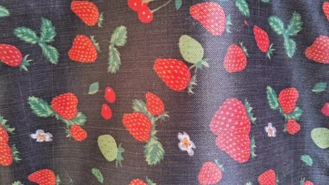Vibrant red strawberry pattern printed on dark smooth textile fabric material Stock Photos