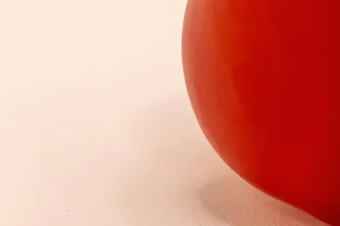 A vibrant red tomato is presented on a light surface, emphasizing its natural Stock Photos
