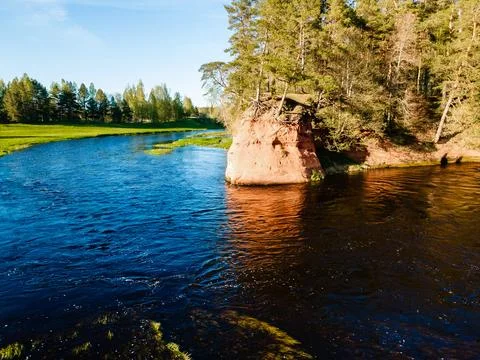 Vibrant river landscape with red cliffs and lush greenery under a clear blu.. Stock Photos