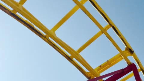 Vibrant Roller Coaster Track Soars High in a Bright Blue Sky Stock Footage 335155576