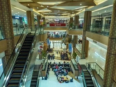 A vibrant shopping mall interior with multiple floors, escalators, and a ce.. Stock Photos