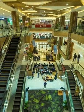 A vibrant shopping mall interior with multiple floors, escalators, and a ce.. Stock Photos
