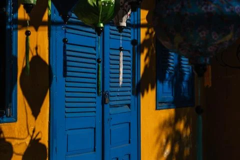 Vibrant silk lanterns hanging in front of a bright blue door on a yellow Photos