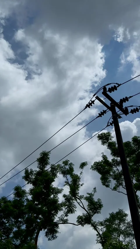 Vibrant sky with fluffy clouds and silhouetted trees against a backdrop of .. Video stock 338414739