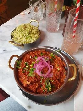 Vibrant spicy pulled chicken curry topped with pickled red onions and fresh h Stock Photos