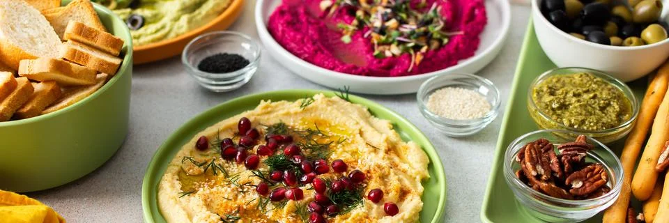 A vibrant spread showcases different types of hummus including classic, beetr Stock Photos