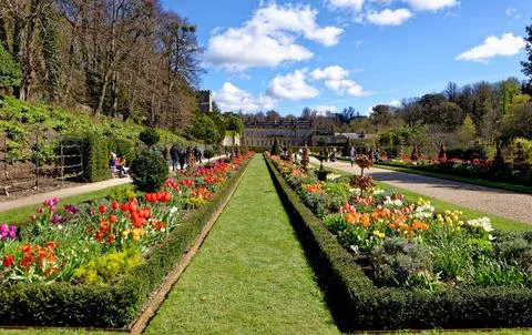 Vibrant spring flower borders and manicured grass paths leading to the hist.. Stock Photos