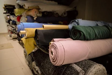 A vibrant stack of multi-colored fabric rolls, arranged in diverse palette... Stock Photos