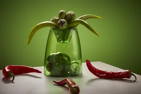 A vibrant still life composition features a green glass vase filled with gr.. 写真素材