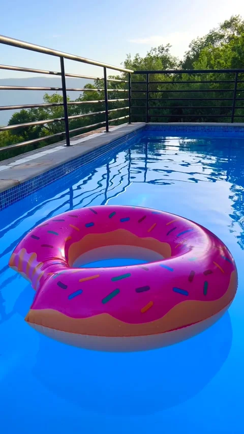 Vibrant Summer Pool Float. Bright donut float in sunny pool. Stock Footage 293057934