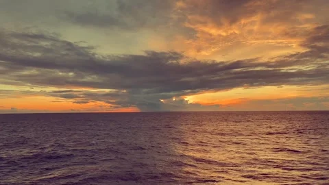 Vibrant sunset casts warm hues over a calm ocean horizon with dramatic clou.. Stock Footage 338280516