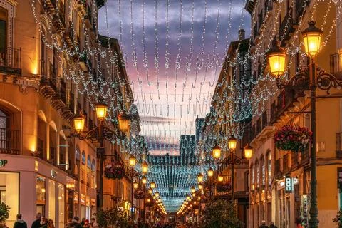 Vibrant sunset clouds glow over the illuminated Calle Alfonso I in Zaragoza Stock Photos