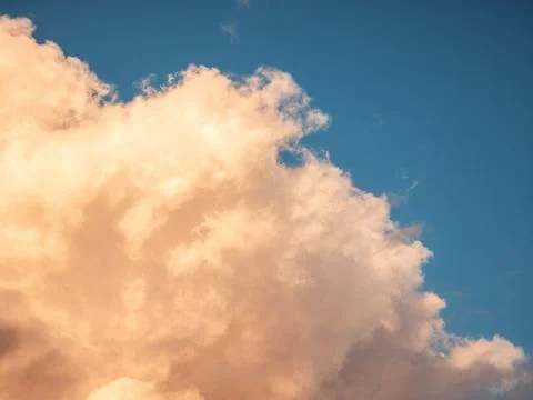 Vibrant sunset clouds with soft, glowing orange tones over deep blue sky Фото