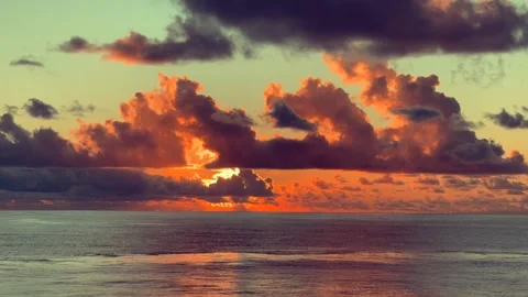 Vibrant sunset with dramatic clouds reflecting over calm ocean waters Stock Footage 338281790