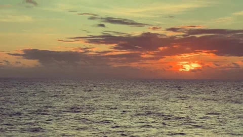 Vibrant sunset over calm ocean with colorful sky and clouds casting a warm .. Stock Footage 338281715