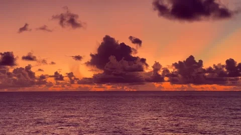 Vibrant sunset over a calm ocean with scattered clouds Stock Footage 338282063