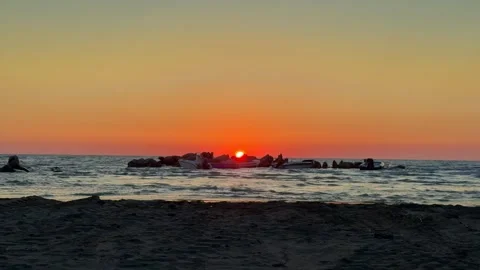 Vibrant sunset over calm sea with rocks and glowing horizon Stock Footage 311831704