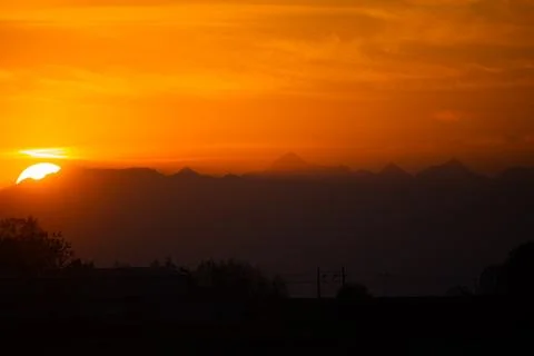 Vibrant Sunset Over Mountain Range with Radiant Orange Sky Stock Photos