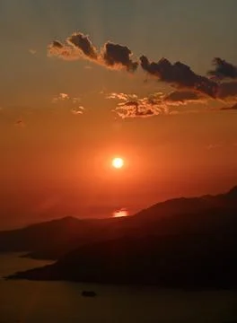 Vibrant sunset over mountain silhouettes and sea bay Stock Photos