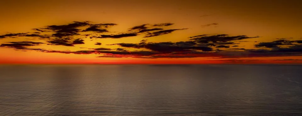 Vibrant sunset over the ocean with dramatic clouds and fiery horizon Foto stock