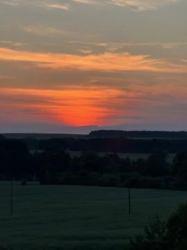Vibrant Sunset Over Rolling Fields and Forest Stock Photos