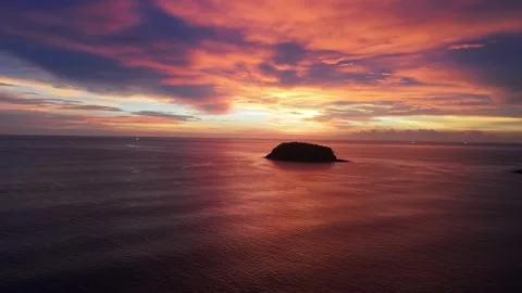Vibrant sunset over tranquil ocean with silhouetted island in the distance Vídeo Stock 337418801
