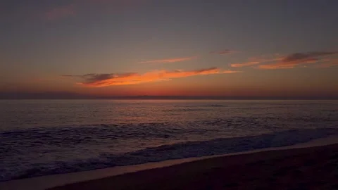 Vibrant sunset paints sky with orange and pink hues above calm sea. Gentle Video stock 337104902