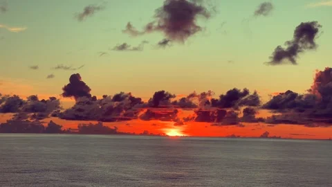 A vibrant sunset paints the sky with orange and red hues over a calm ocean .. 動画素材 338282809