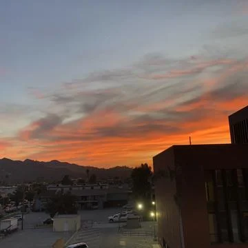Vibrant Sunset Paints the Sky Over Cityscape With Mountains in the Distance Foto stock