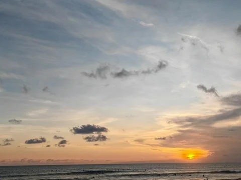 Vibrant sunset sky with dramatic clouds over the calm ocean horizon Stock Photos