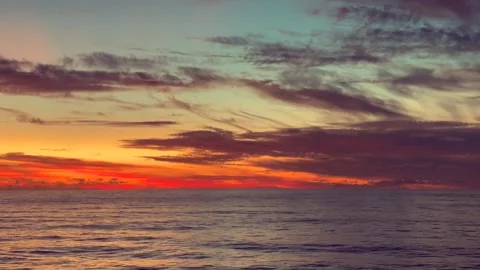 Vibrant sunset sky reflecting over calm ocean waters with colorful clouds c.. Stock Footage 338282035